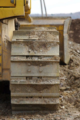 heavy machinery bulldozer treads covered in dirt and mud and ready for power washing